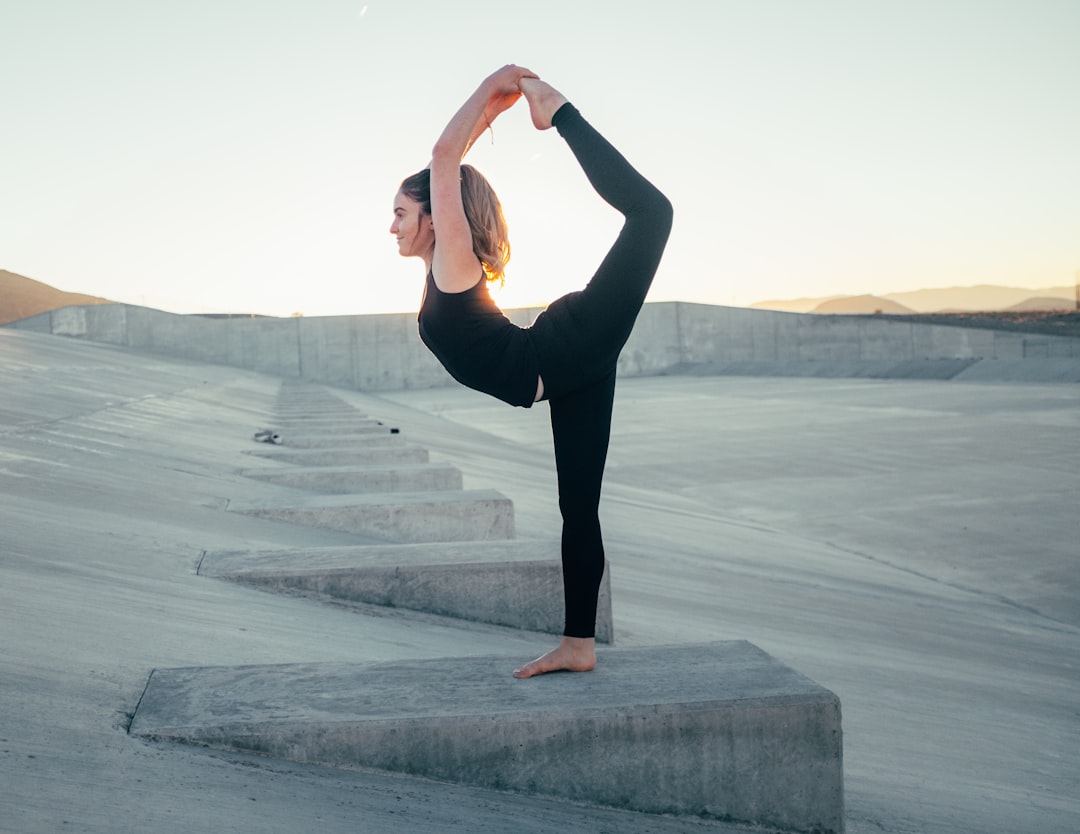 Image must show ONLY what this section discusses: recorded lessons providing flexibility and accessibility for Feldenkrais practice anytime, anywhere. A person is practicing Feldenkrais outdoors in a park or on a balcony, with headphones on and a smartphone or small portable speaker nearby, symbolizing the 'anytime, anywhere' accessibility of recorded lessons.. Photorealistic, high-quality photography style. אדם מתרגל פלדנקרייז בחוץ בפארק עם אוזניות, הממחיש את הגמישות והנגישות של שיעורים מוקלטים.