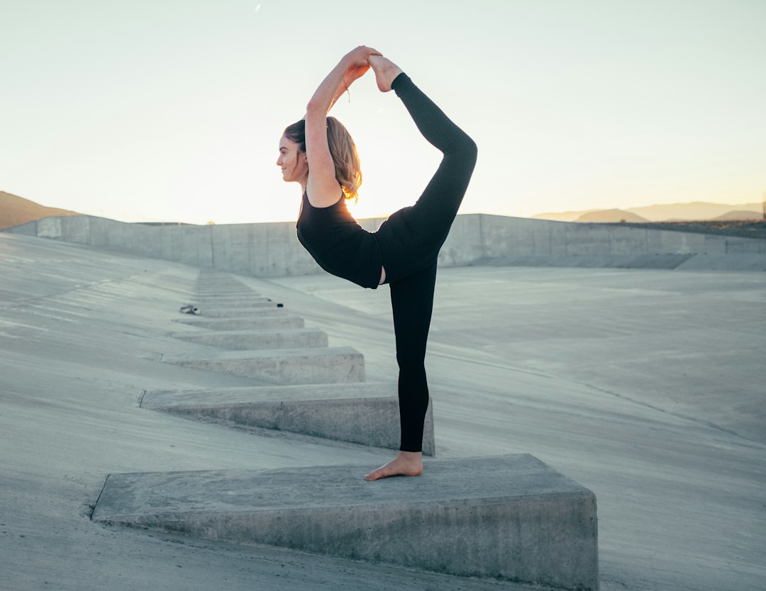 Image must show ONLY what this section discusses: recorded lessons providing flexibility and accessibility for Feldenkrais practice anytime, anywhere. A person is practicing Feldenkrais outdoors in a park or on a balcony, with headphones on and a smartphone or small portable speaker nearby, symbolizing the 'anytime, anywhere' accessibility of recorded lessons.. Photorealistic, high-quality photography style. אדם מתרגל פלדנקרייז בחוץ בפארק עם אוזניות, הממחיש את הגמישות והנגישות של שיעורים מוקלטים.